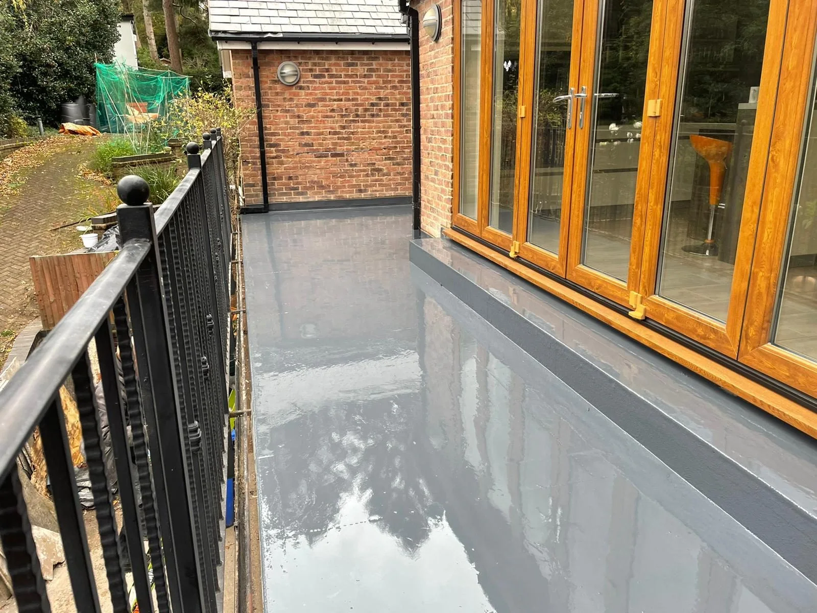 Grey balcony surface beside timber framed glazed doors and metal railings