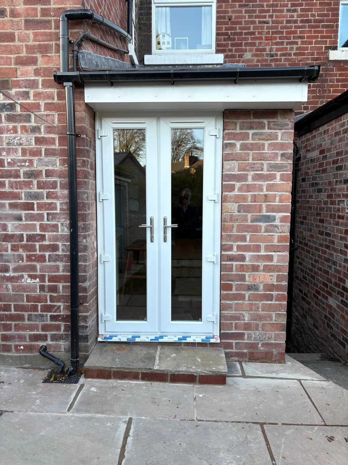 White French doors in a new brick rear extension with stone step and patio