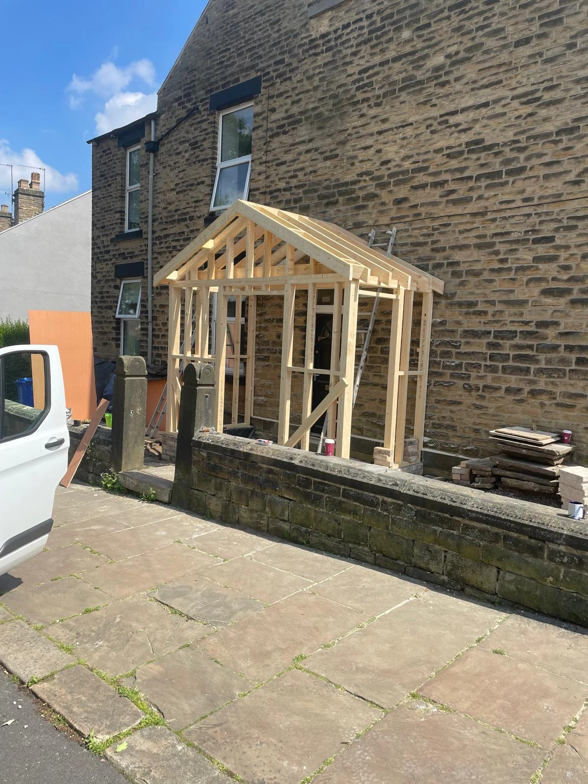 Timber porch framework beside a stone house