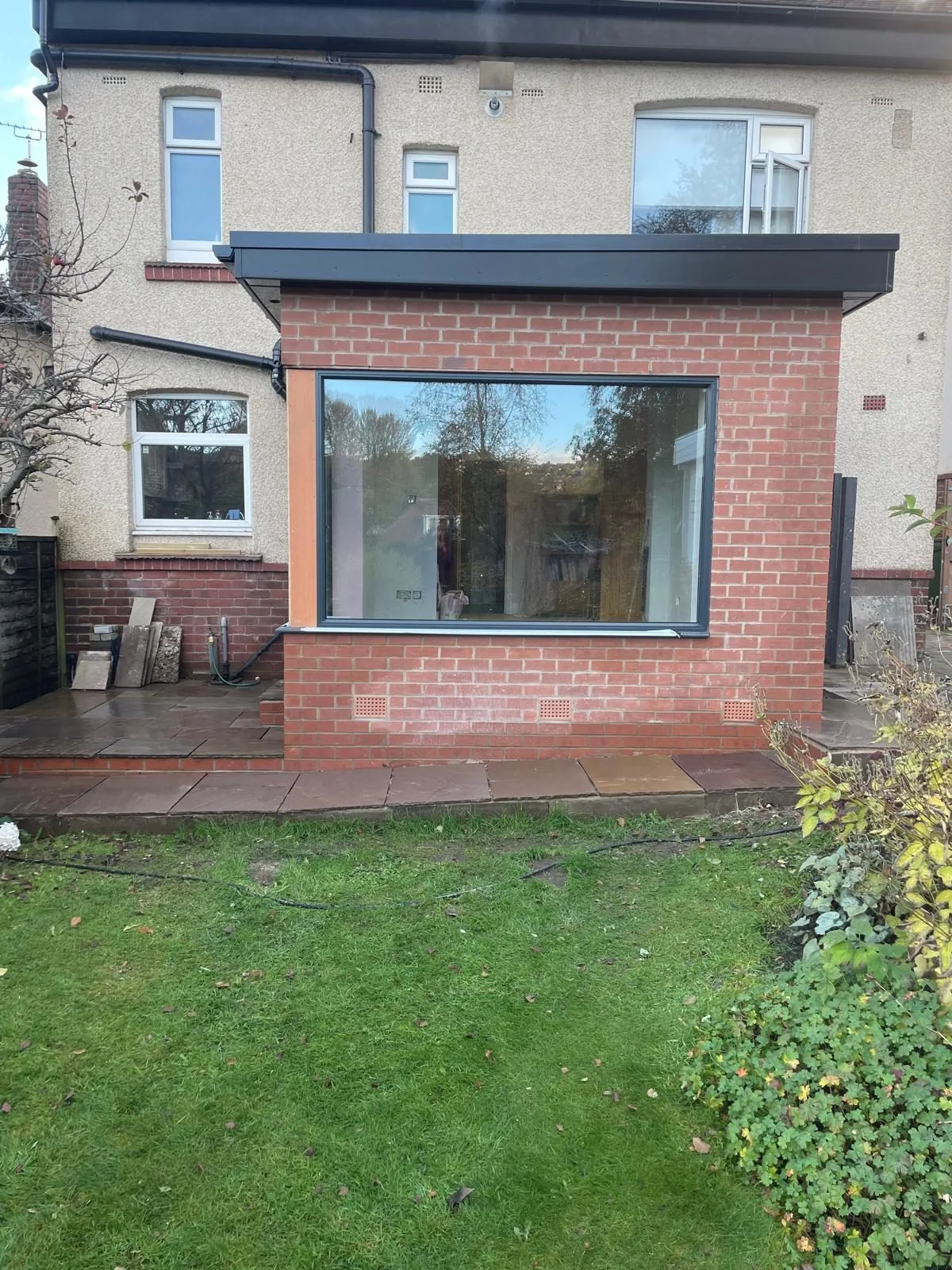 Completed brick rear extension with large window and dark roof trim
