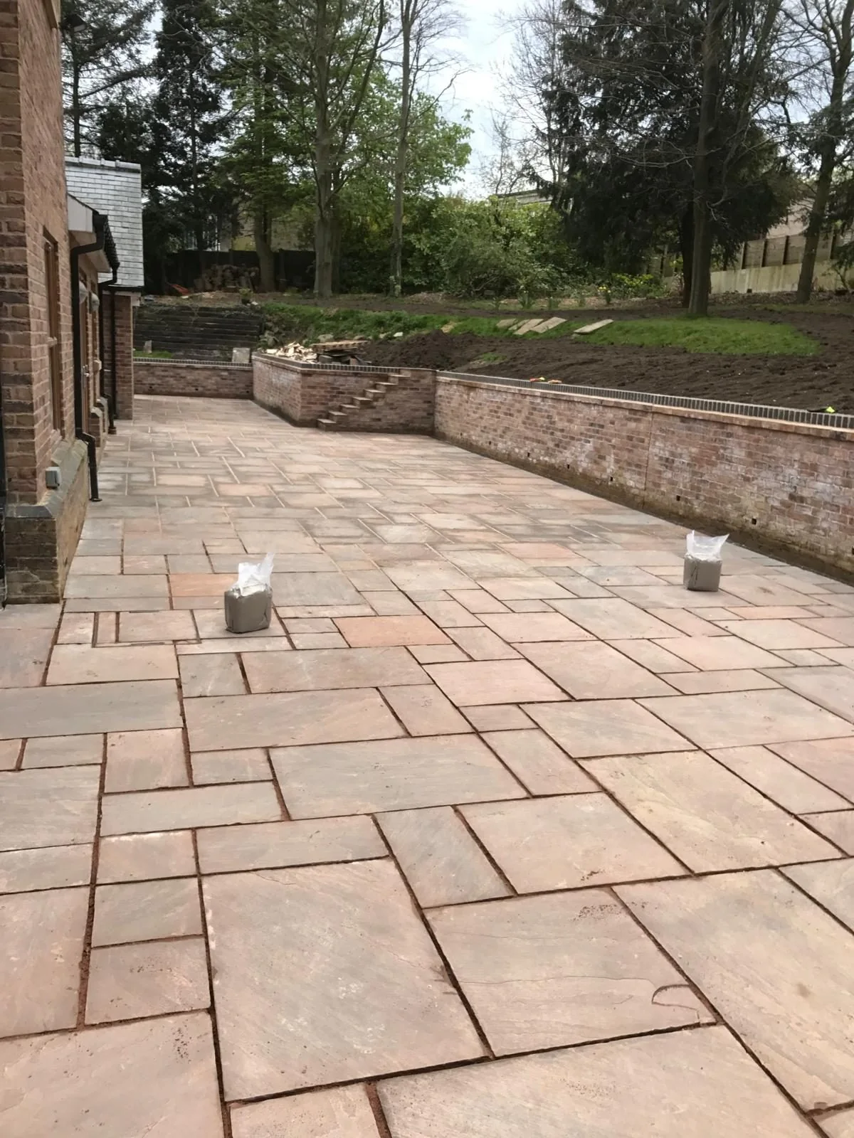 Paved garden terrace beside a brick house with curved retaining wall