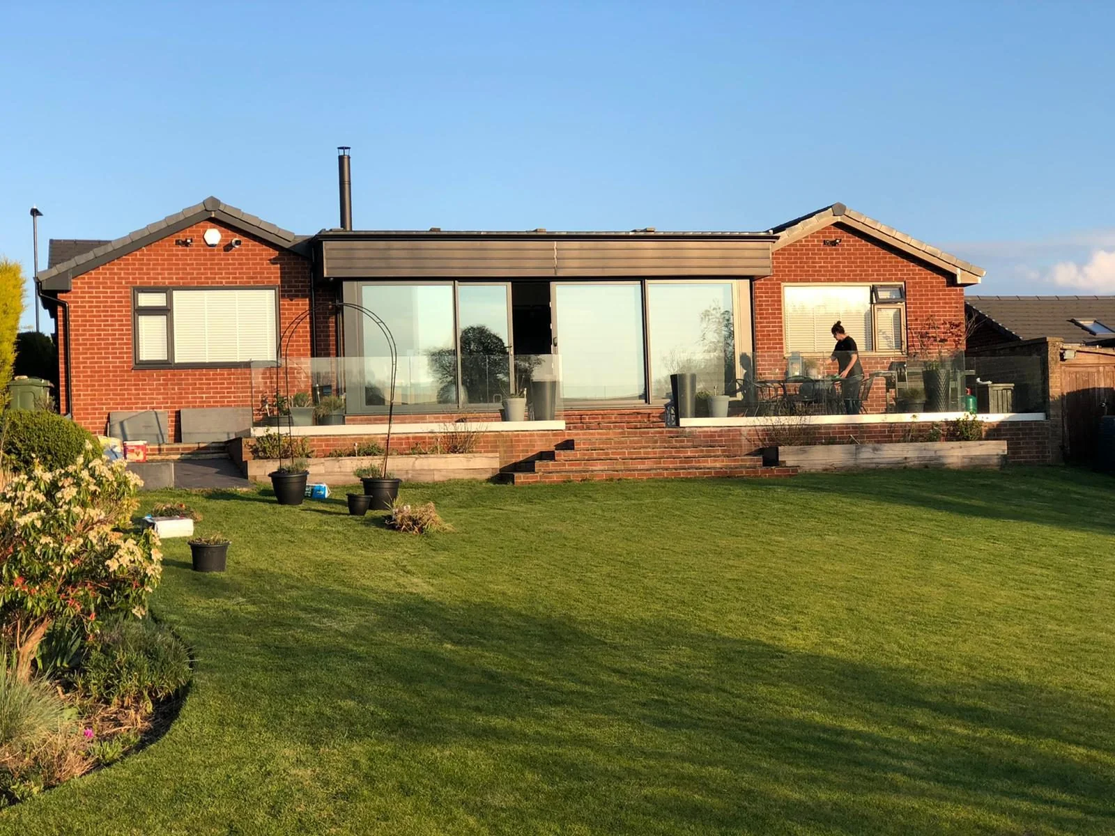 Red brick bungalow extension with wide glazing and raised terrace